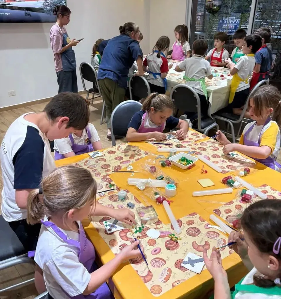 Chicos decorando en una mesa larga, cada uno con su tabla