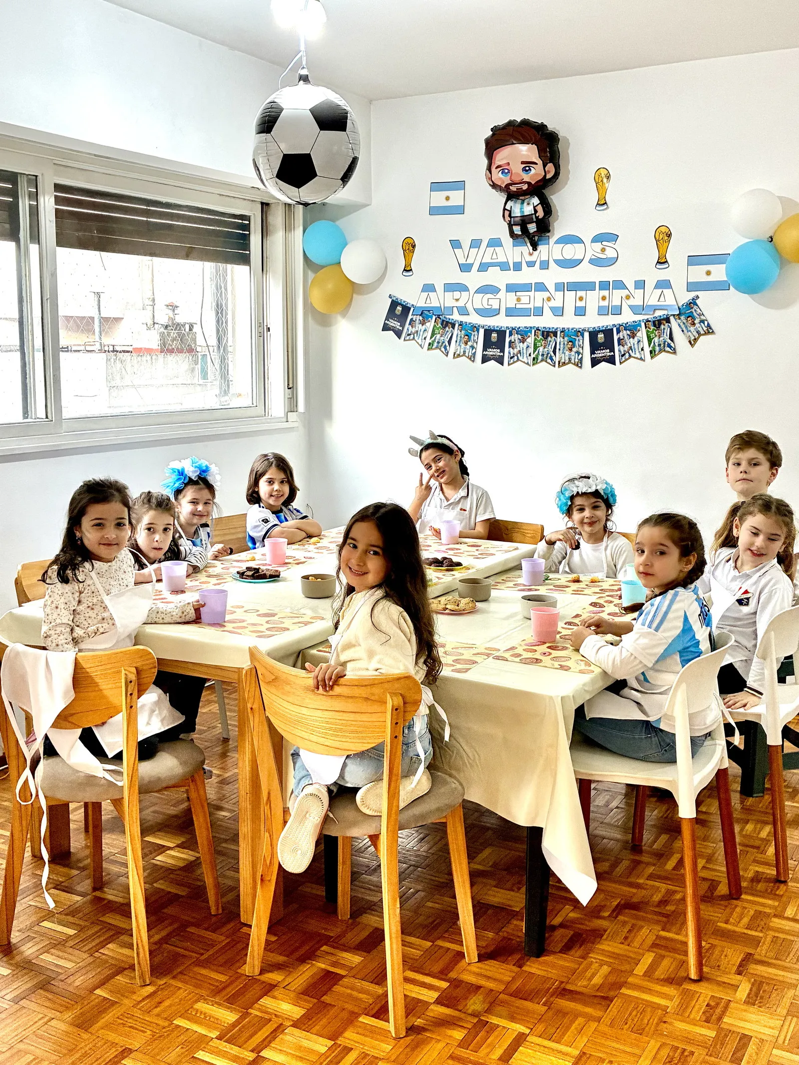 La mesa larga armada para un cumpleaños, con los chicos sentados alrededor