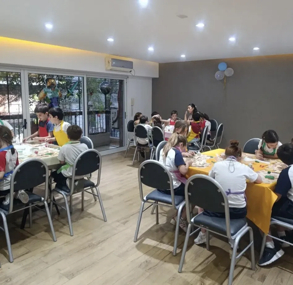 Un salón con dos mesas de chicos cocinando